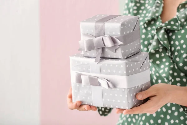 Woman holding gift boxes on color background, closeup — Stock Photo, Image