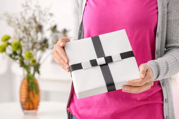 Woman holding gift box on blurred background — Stock Photo, Image