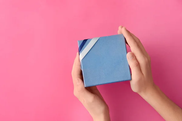 Woman holding gift box on color background, top view — Stock Photo, Image