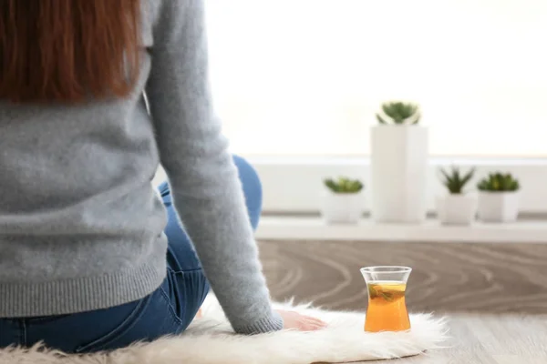 Taza de té caliente y mujer sentados en el suelo en casa — Foto de Stock