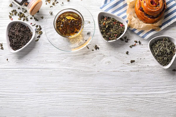 Flat lay composition with dry tea leaves and hot beverage on wooden background — Stock Photo, Image