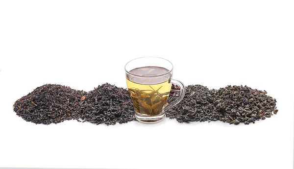 Different kinds of dry tea leaves and cup with hot beverage on white background — Stock Photo, Image