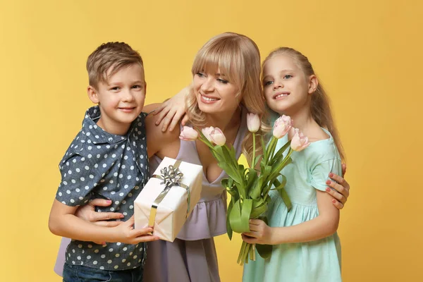 Портрет милых маленьких детей и их матери с подарками на цветном фоне — стоковое фото