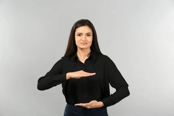 Young businesswoman holding something on gray background — Stock Photo, Image