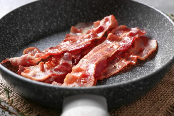 Pfanne mit leckerem Speck auf dem Tisch, Nahaufnahme — Stockfoto