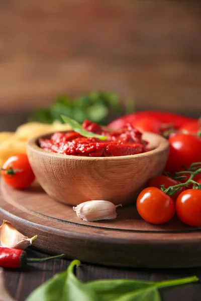 Bowl with red sauce and vegetables on table — Stock Photo, Image