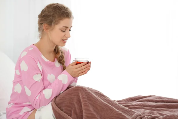 Mladá žena pít čaj v posteli — Stock fotografie