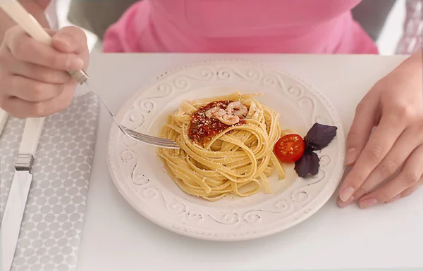 Mujer joven comiendo pasta sabrosa en la mesa, primer plano — Foto de Stock