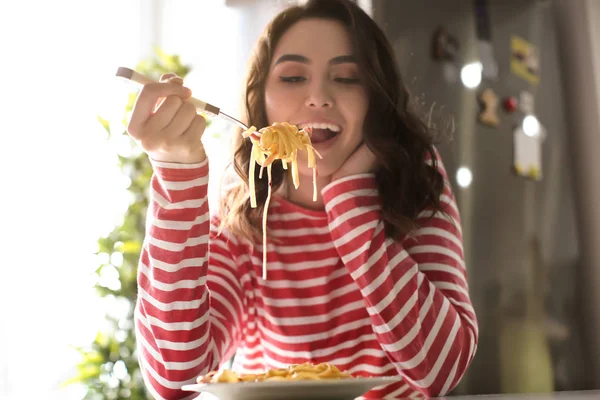 Jovem mulher comendo massa saborosa em casa — Fotografia de Stock