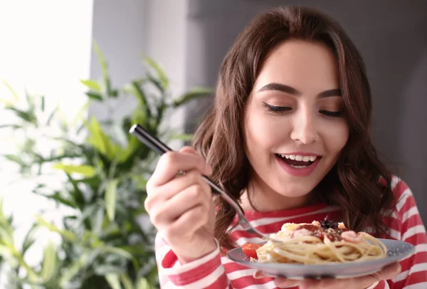 Mujer joven comiendo pasta sabrosa en casa — Foto de Stock