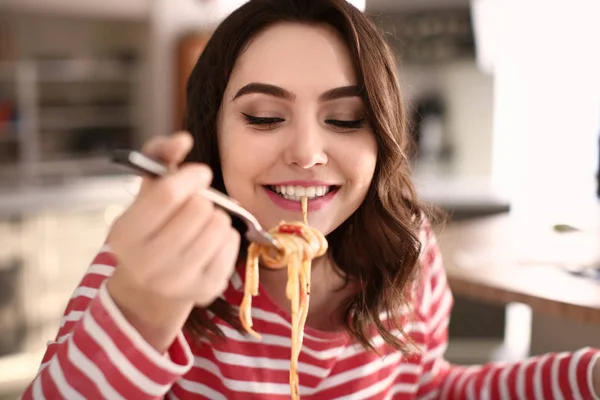 Jovem mulher comendo massa saborosa em casa — Fotografia de Stock