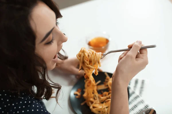 Jovem mulher comendo massa saborosa à mesa — Fotografia de Stock
