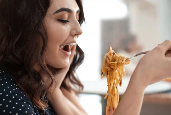 Молодая женщина ест вкусную пасту в кафе — стоковое фото