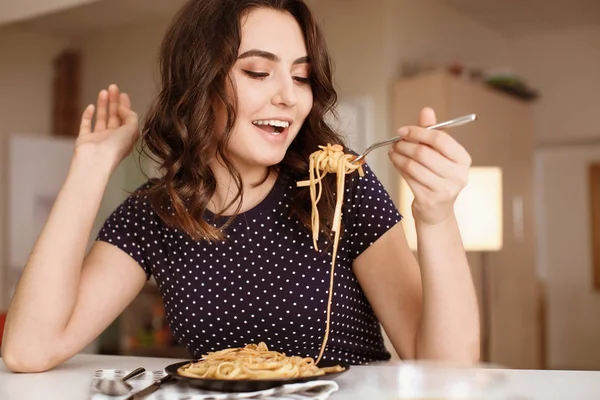 Mujer joven comiendo pasta sabrosa en la mesa — Foto de Stock