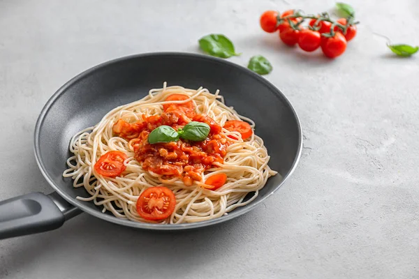 Frying pan with delicious pasta and tomato sauce on table — Stock Photo, Image