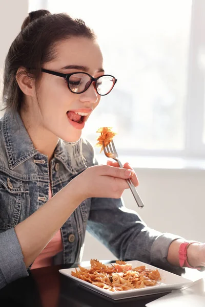 Mujer joven comiendo deliciosa pasta en el interior — Foto de Stock