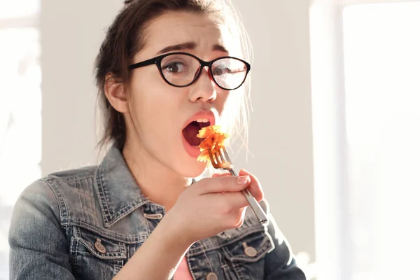 Mujer joven comiendo deliciosa pasta en el interior — Foto de Stock
