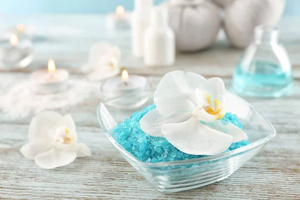 Bowl with sea salt for spa procedures and beautiful flower on wooden table — Stock Photo, Image