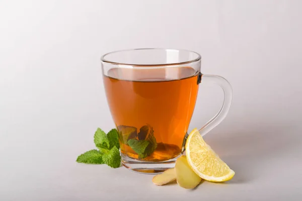 Cup of delicious tea with mint, ginger and lemon on grey background — Stock Photo, Image