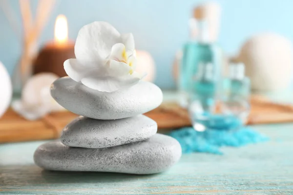 Spa stones with beautiful flower on wooden table — Stock Photo, Image