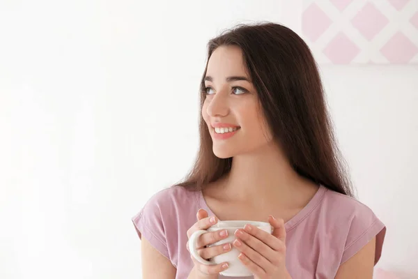 Piękna młoda kobieta z kubkiem gorącej herbaty w domu — Zdjęcie stockowe