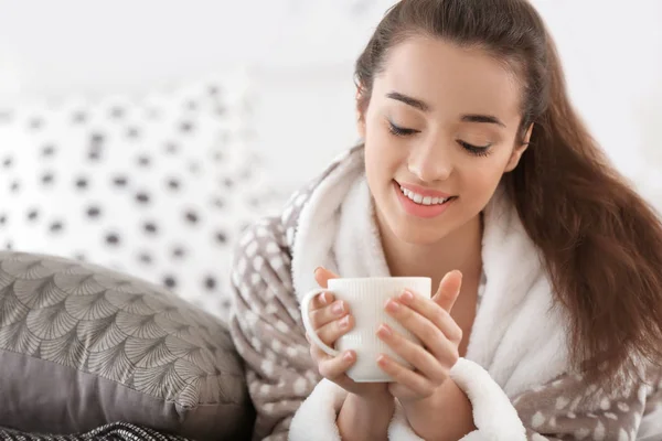 Piękna młoda kobieta z kubkiem gorącej herbaty w domu — Zdjęcie stockowe