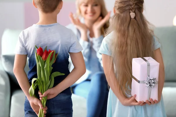 Little kids hiding gifts for mother behind their backs at home — Stock Photo, Image