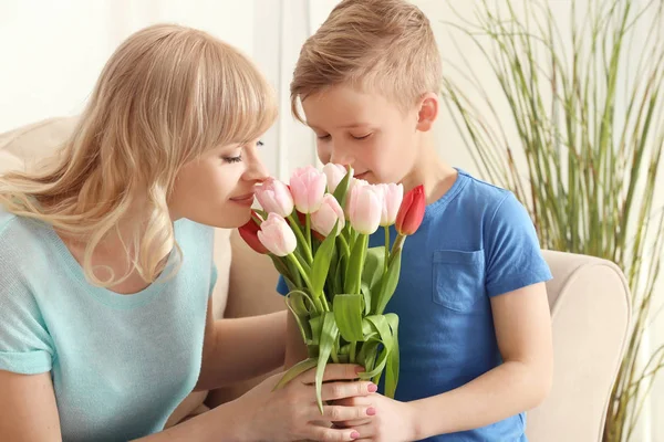 Portret van schattige kleine jongen en zijn moeder met tulip boeket thuis — Stockfoto