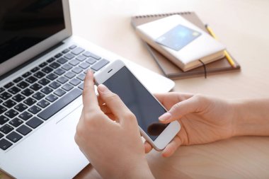 Masada akıllı telefon kullanan genç bir kadın.