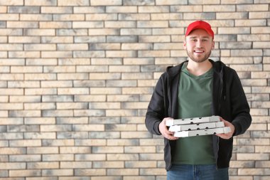 Karton pizza kutuları tuğla duvar arka plan üzerinde olan genç adam. Gıda dağıtım hizmeti