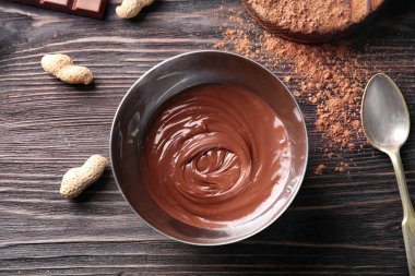 Ahşap masa üzerinde lezzetli eritilmiş çikolata ile kase