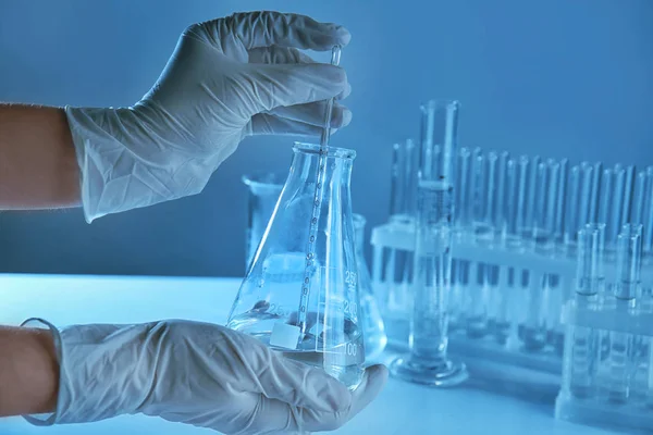 Cientista segurando frasco cônico com líquido e pipeta em laboratório — Fotografia de Stock