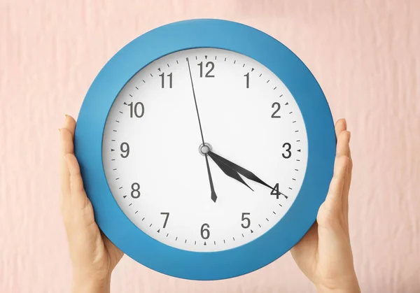 Frau hält Uhr auf farbigem Hintergrund. Zeitmanagement-Konzept — Stockfoto