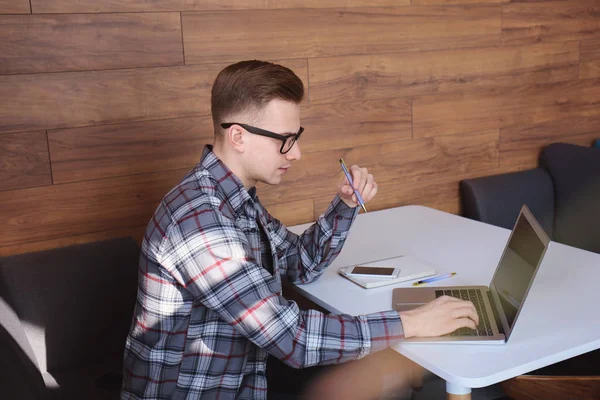 Young freelancer working with laptop at table in cafe — Stock Photo, Image