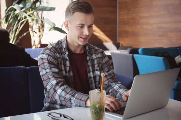 Νέος ελεύθερος επαγγελματίας εργάζεται με το laptop στο τραπέζι στην καφετέρια — Φωτογραφία Αρχείου