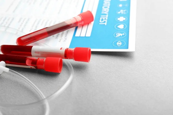 Tubos de ensaio com amostras de sangue e equipamento médico sobre fundo claro — Fotografia de Stock