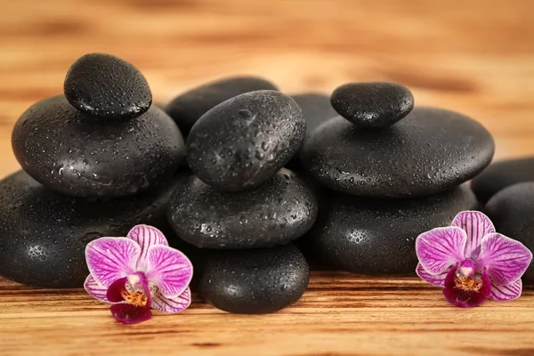 Spa stones with orchid flowers on wooden table — Stock Photo, Image