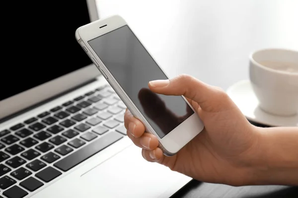 Young woman using smartphone at table — Stock Photo, Image