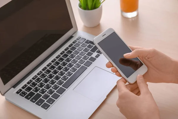 Jonge vrouw met smartphone aan tafel — Stockfoto