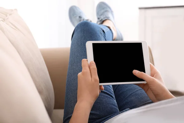 Mujer joven usando tableta mientras descansa en el sofá en casa — Foto de Stock
