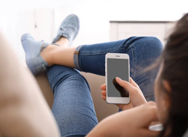 Young woman using smartphone while resting on couch at home — Stock Photo, Image