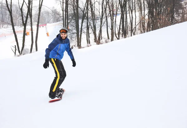 Αρσενικό snowboarder σε πλαγιά στο χειμερινό θέρετρο — Φωτογραφία Αρχείου