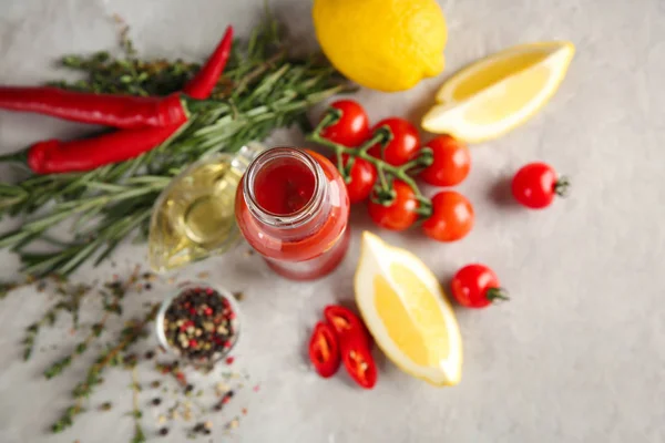 Composizione con bottiglia di gustosa salsa e verdure su fondo grigio — Foto Stock