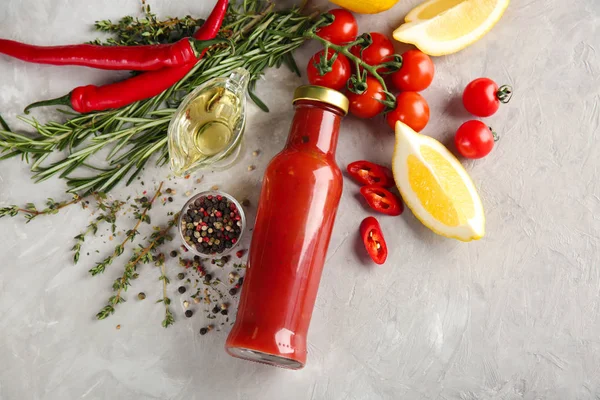 Composizione con bottiglia di gustosa salsa e verdure su fondo grigio — Foto Stock