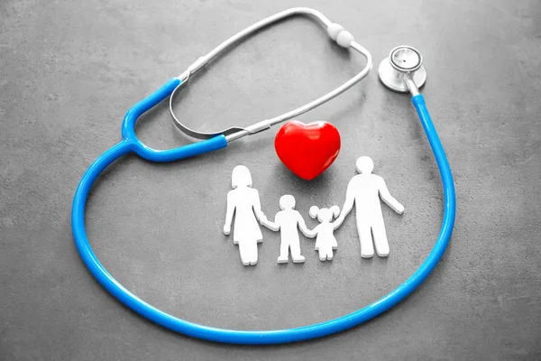 Figura di famiglia, cuore rosso e stetoscopio su sfondo grigio. Concetto sanitario — Foto Stock