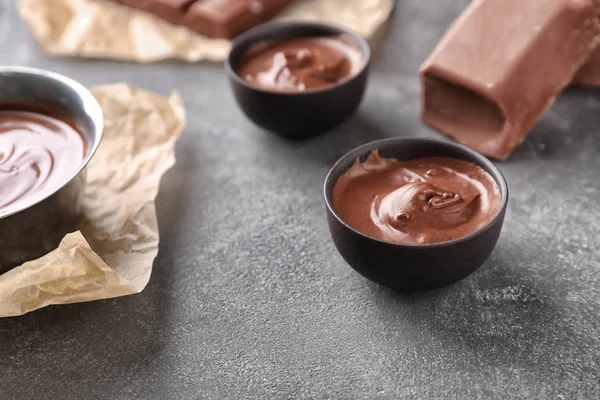 Bowls with tasty melted chocolate on grey table — Stock Photo, Image