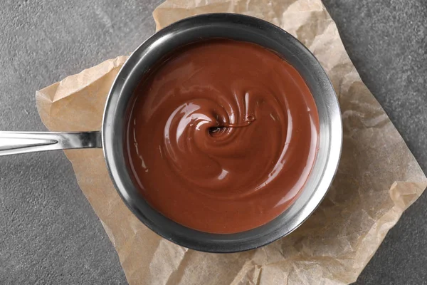 Bowl dengan coklat meleleh lezat di meja abu-abu, pandangan atas — Stok Foto