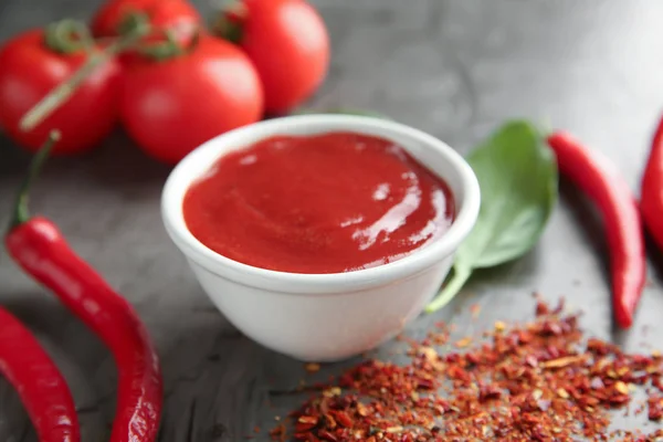Schüssel mit roter Sauce und Gemüse auf grauem Hintergrund — Stockfoto