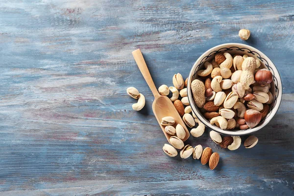 Bowl with different nuts on wooden background — Stock Photo, Image