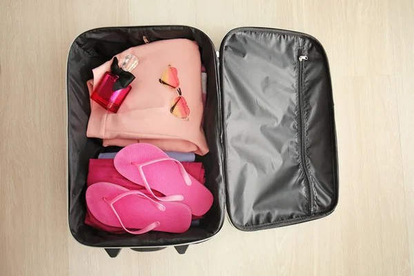 Открытый чемодан с упакованными вещами на полу, вид сверху — стоковое фото